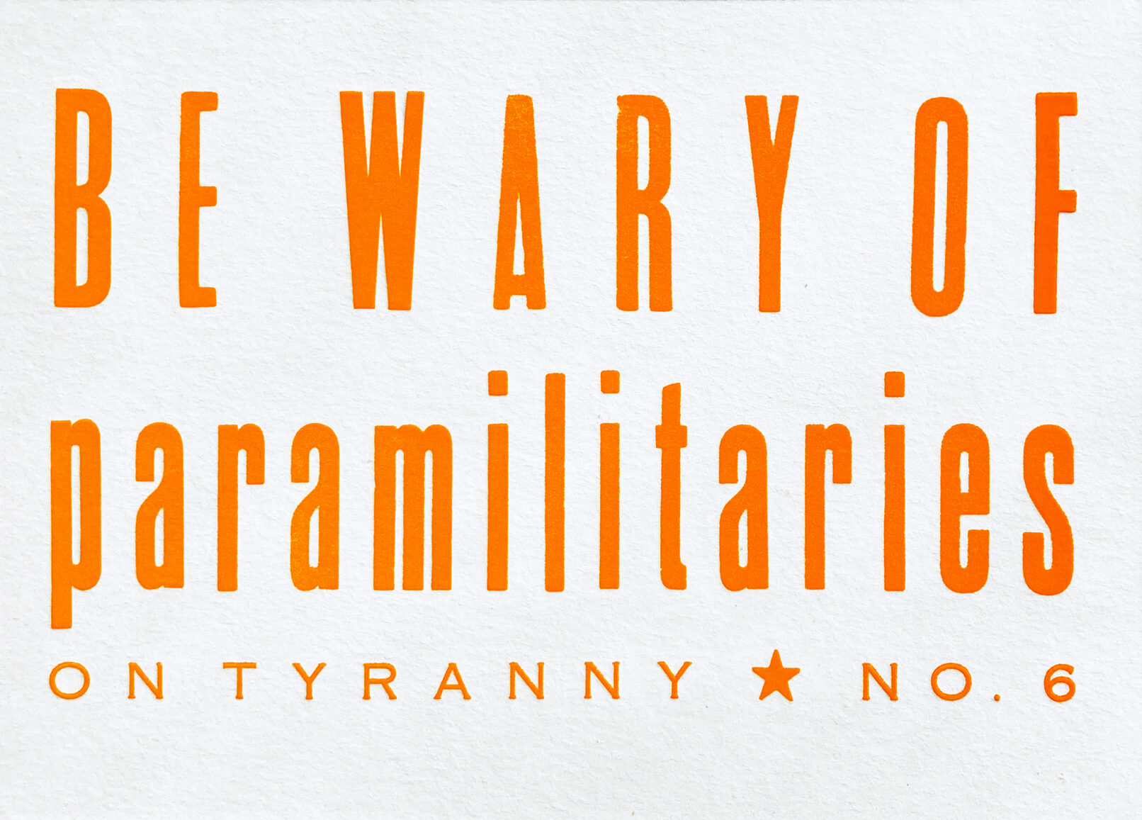 Letterpress print on Vandercook press bed. Printed in orange ink on white paper, the text reads "Be Wary Of Paramilitaries On Tyranny No. 6."