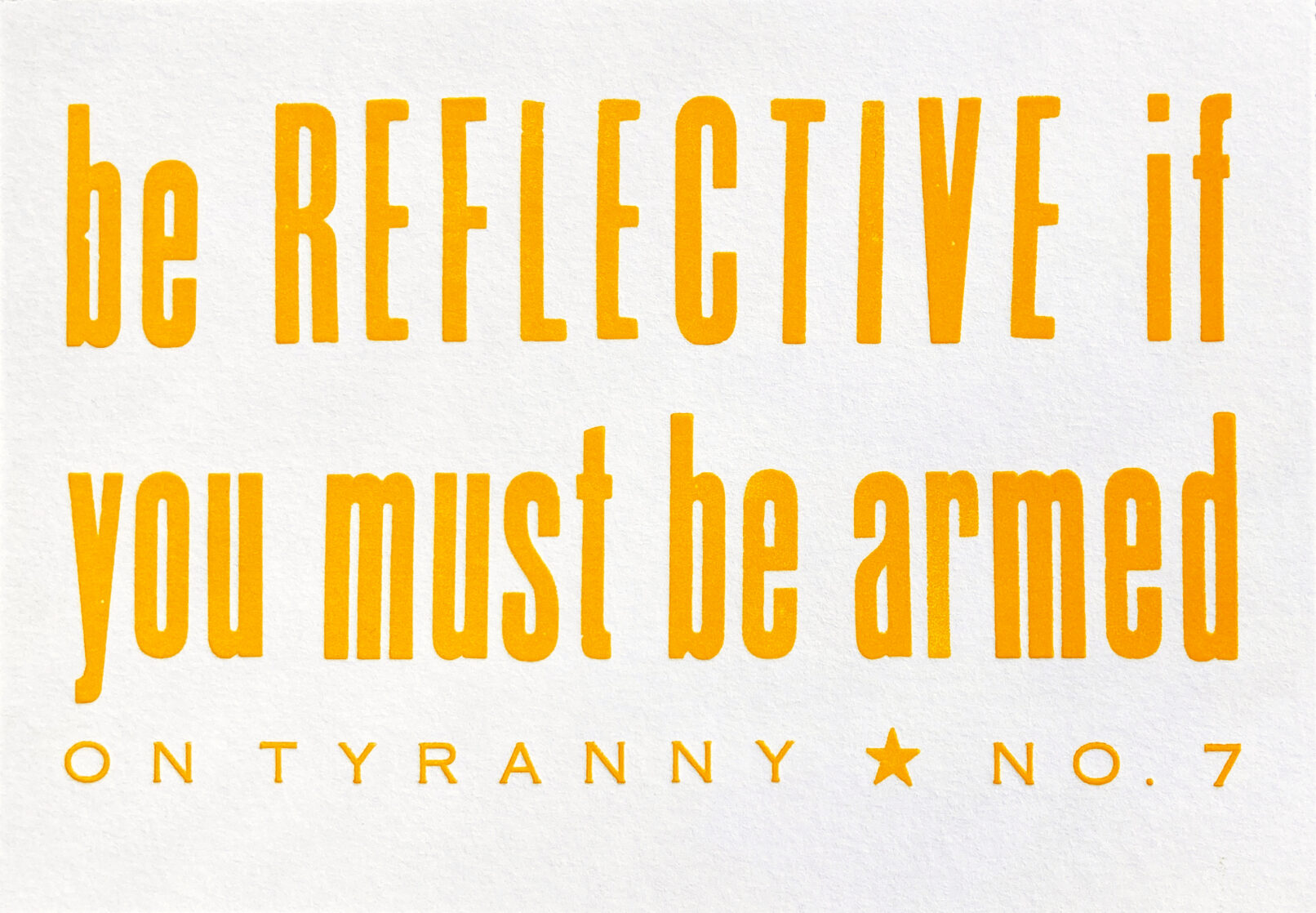 Letterpress print in yellow-orange ink on white paper with text that reads "Be Reflective if You Must be Armed On Tyranny No. 7"